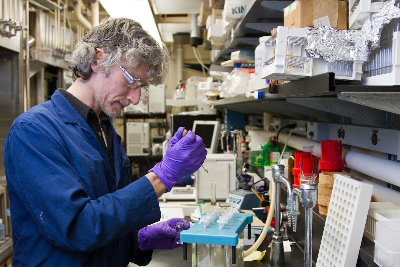 Técnico de jaleco e luvas analisando amostras em um laboratório