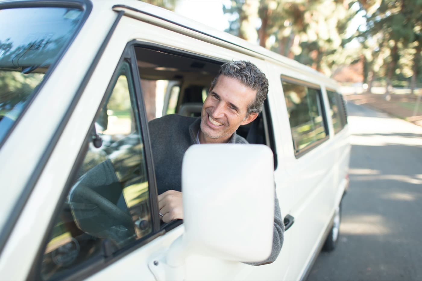 Motorista sorrindo apoiado na janela do veículo