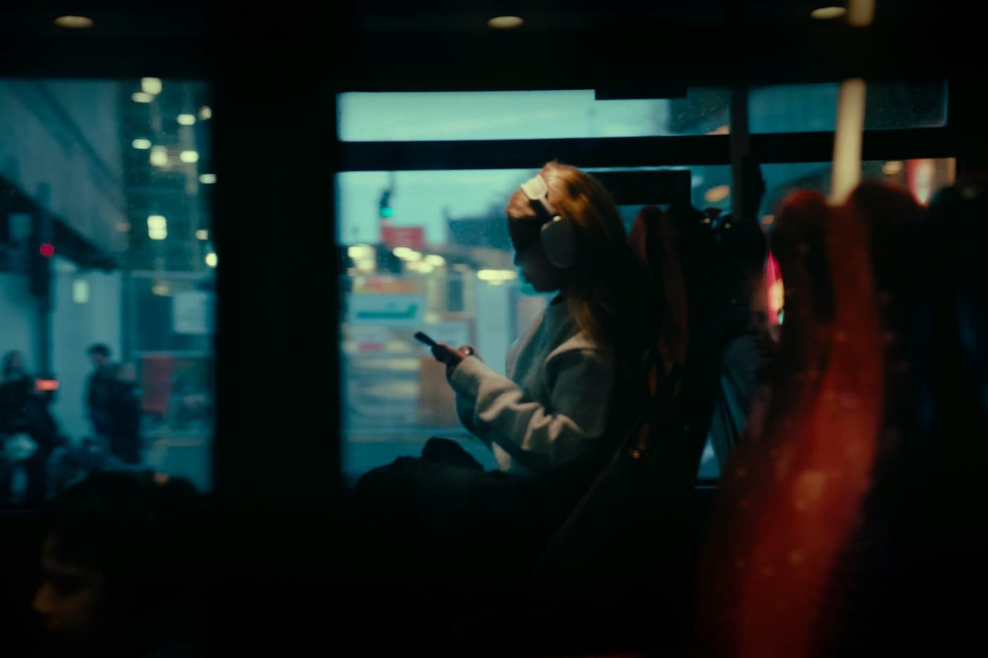 Passageira olhando o celular dentro de um ônibus à noite