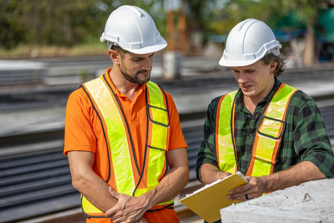 Dois engenheiros de capacete e colete refletivo conferindo o planejamento no canteiro de obras