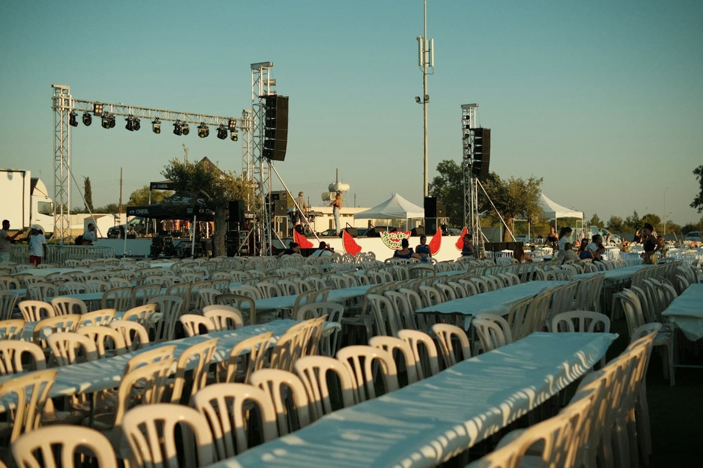 Estrutura de palco, som e fileiras de cadeiras montadas para um evento ao ar livre