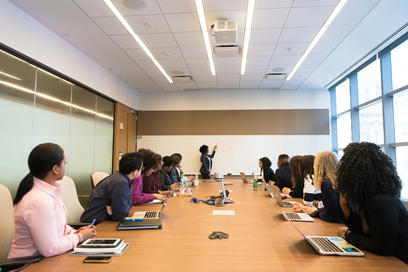 Profissionais reunidos em uma mesa de reunião acompanhando uma apresentação