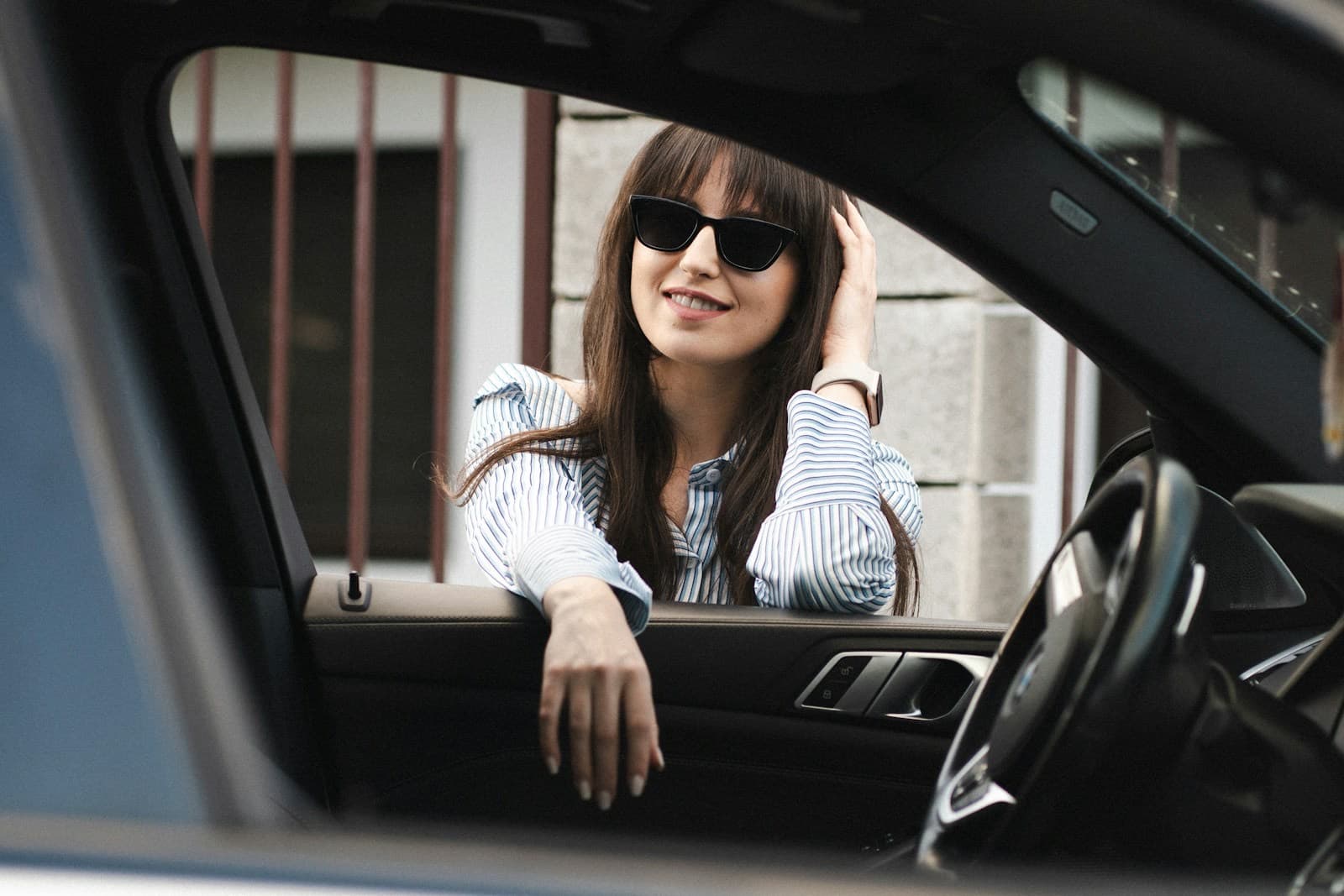 Mulher sorrindo apoiada na janela do carro