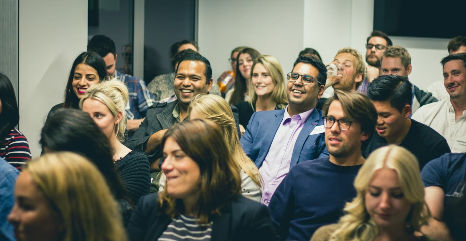 Plateia sorridente acompanhando um evento corporativo
