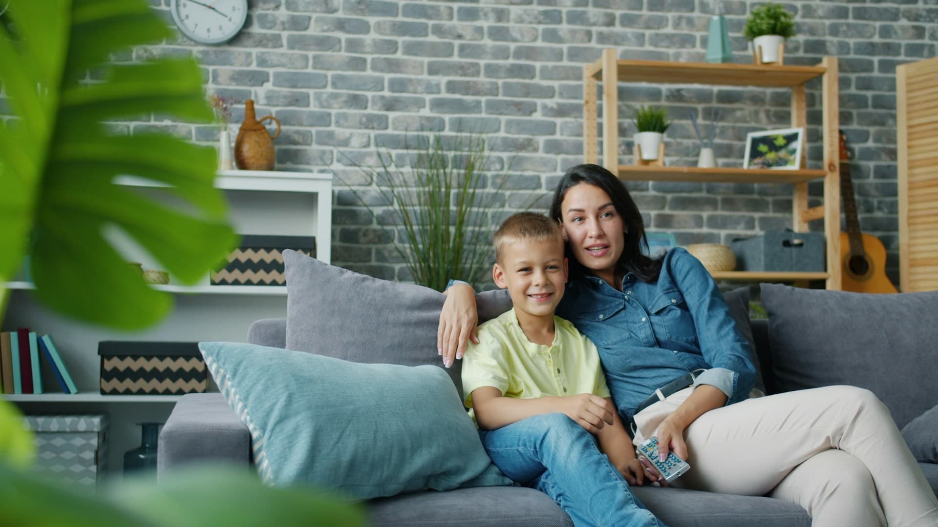 Mãe e filho sorrindo abraçados no sofá da sala