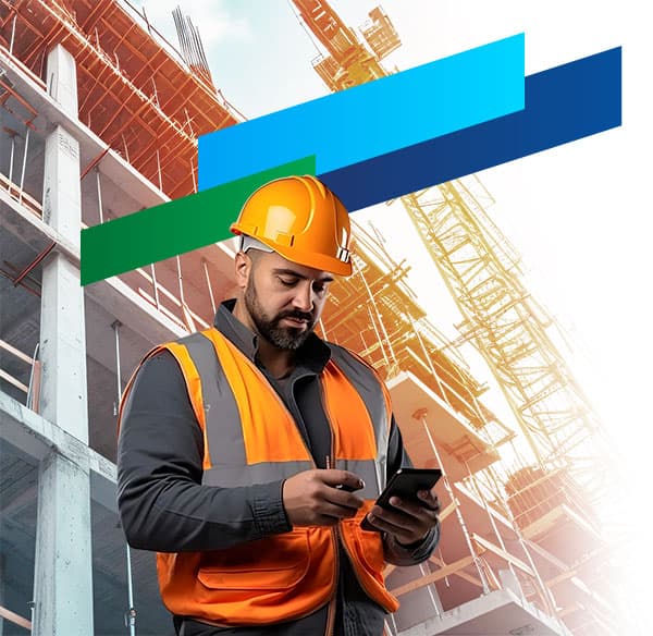 Engenheiro de capacete e colete consultando o celular em frente a um edifício em construção