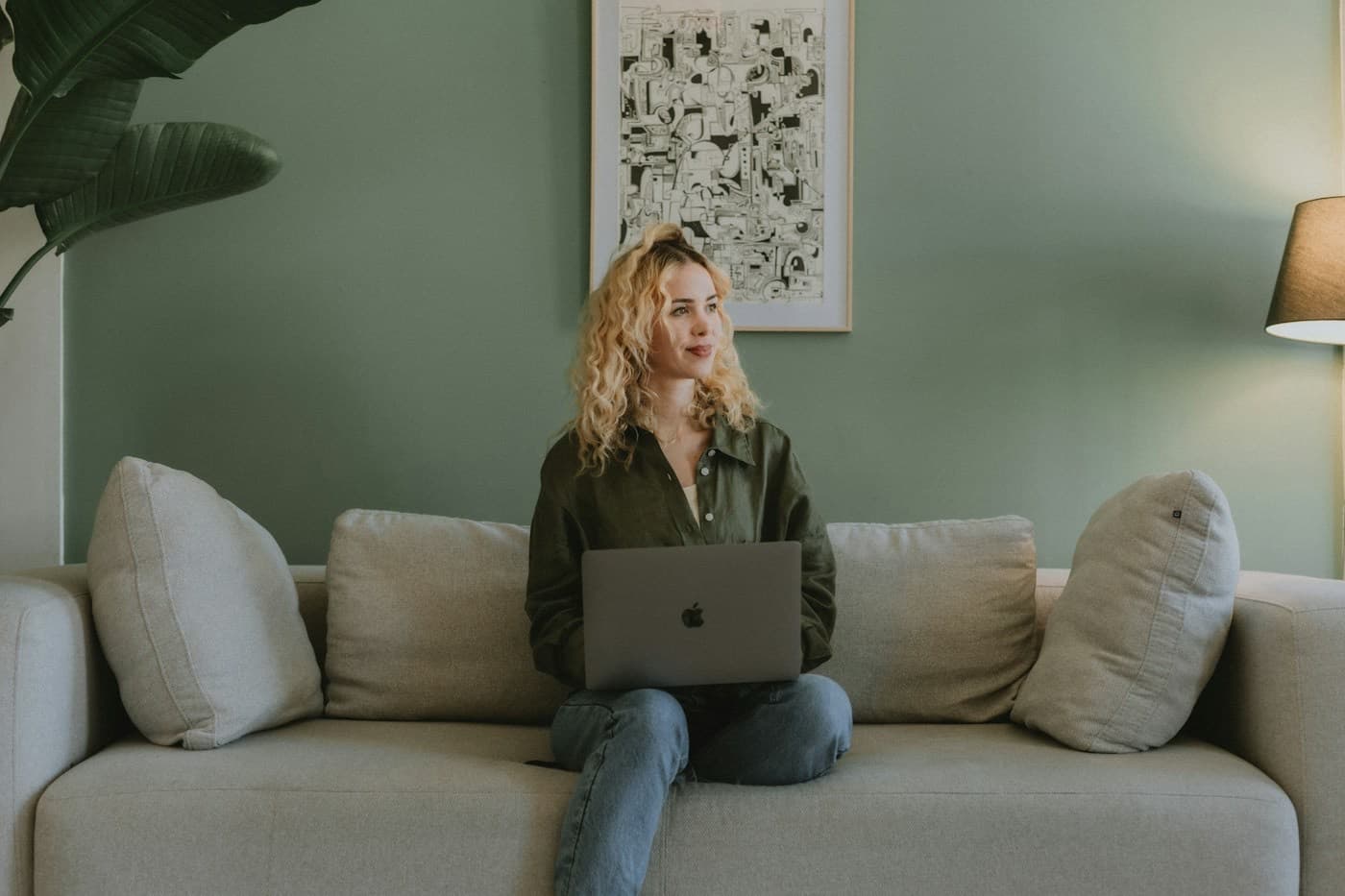 Mulher sentada no sofá de casa em uma consulta online pelo notebook