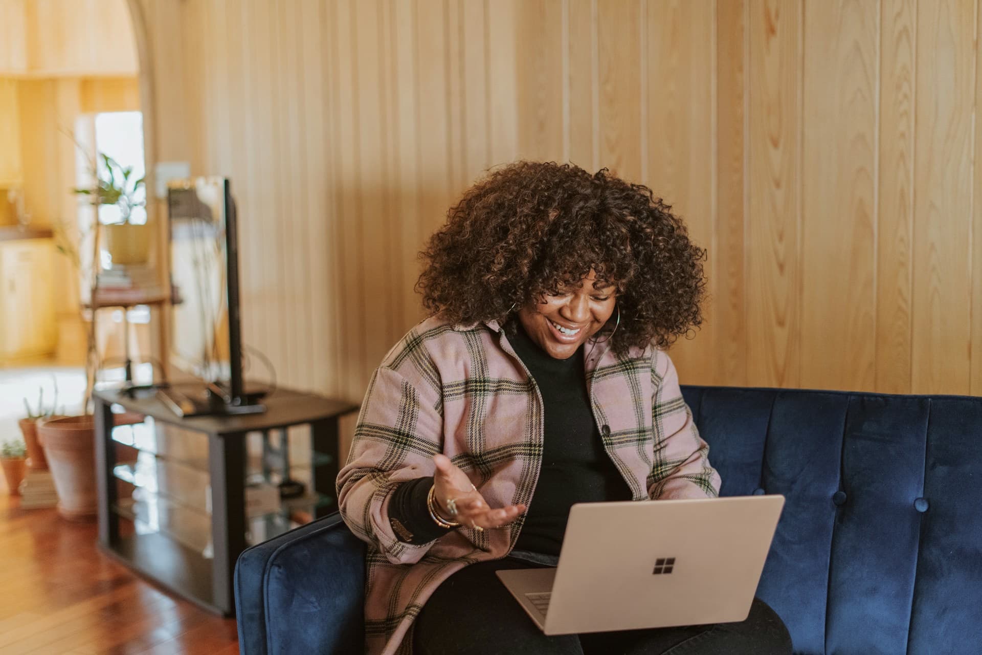 Mulher sorrindo durante uma chamada de vídeo pelo notebook, na sala de casa